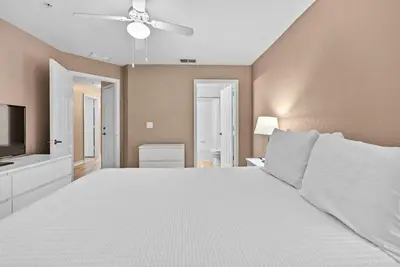 a bedroom with a large white bed with a ceiling fan at Cozy Themed 04 bedrooms - Close to Disney in Kissimmee