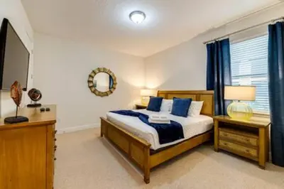 a bedroom with a bed with blue pillows and a mirror at RVH7391 - Five Bed Luxury Disney Vacation Retreat in Orlando