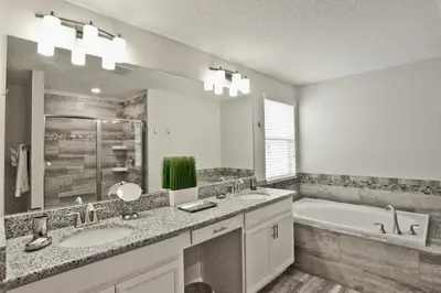 a bathroom with two sinks and a tub and a mirror at Private Heated Pool Water View Resort Fun Near Disney in Kissimmee