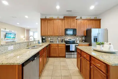a kitchen with wooden cabinets and stainless steel appliances at Magical Getaway Near Disney I Pool and Fun Room in Orlando