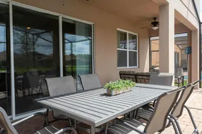 a wooden table and chairs on a patio at Casa Familiar c/ Piscina 9 Quartos Perto Disney in Kissimmee