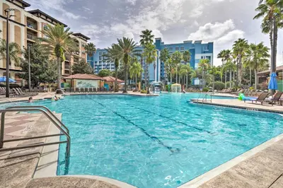 a large swimming pool with palm trees and buildings at Floridays Resort Condo 11 Mi to Walt Disney World! in Orlando