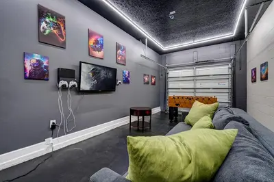 a living room with a couch and a tv on a wall at NEW, Disney,10mi, Themed Rooms, PvtPool, Movie, Game Room in Kissimmee