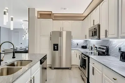 a kitchen with white cabinets and a stainless steel refrigerator at Luxo no Vista Cay | 4 quartos perto da Universal in Orlando