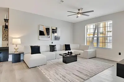 a living room with white furniture and a ceiling fan at Luxo no Vista Cay | 4 quartos perto da Universal in Orlando