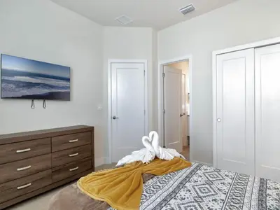 a white bedroom with a bed and a dresser at TR17226BD - 4 bedr w/pool - 10 guests Near Disney in Orlando