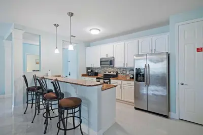 a kitchen with white cabinets and a stainless steel refrigerator at Seaescape in Orlando