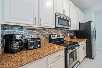 a kitchen with white cabinets and a black appliances at Seaescape in Orlando