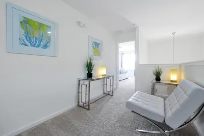 a white living room with a white chair and two tables at 2616 TRANQUILITY KISSIMMEE 6 BED in Kissimmee