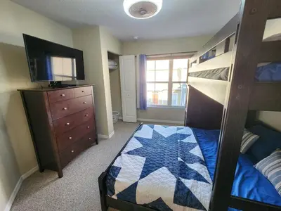 a bedroom with a bunk bed and a dresser and a television at 3 Bedroom 2 Bathroom Villas At Seven Dwarfs 20-104 in Kissimmee