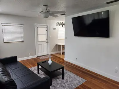 a living room with a black couch and a flat screen tv at Sunny Retreat in Orlando