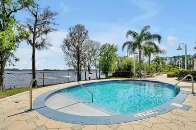 a swimming pool with trees and a body of water at Disney Dream Condo & Lake View Awaits in Orlando