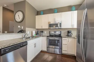 a kitchen with white cabinets and a clock on the wall at TVPM-3230WA in Kissimmee