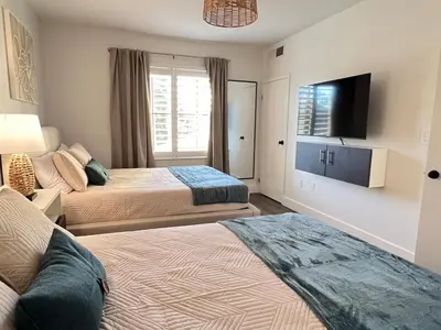 a hotel room with two beds and a flat screen tv at Suite near Epic Universe & Universal, free parking in Orlando