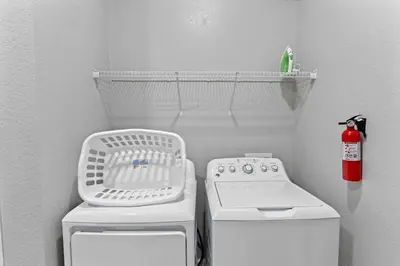 a small bathroom with a washing machine and a drying rack at Amplo apê 4 quartos no Vista Cay Resort in Orlando