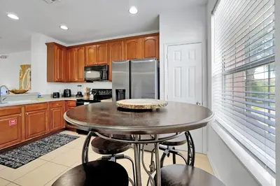 a kitchen with a table and a stainless steel refrigerator at Beautiful Epic Universe Townhome, Vista Cay-4034 in Orlando