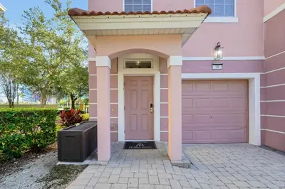 a pink house with a door and a garage at Beautiful Epic Universe Townhome, Vista Cay-4034 in Orlando