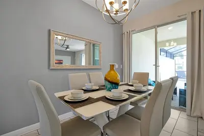 a dining room with a table with chairs and a vase at 5017 WINDERMERE 4BED in Kissimmee