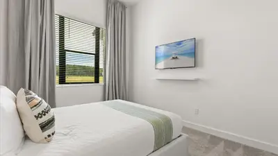 a white bedroom with a bed and a window at Lakeside Villa with Pool BBQ Cinema & Games Room in Kissimmee
