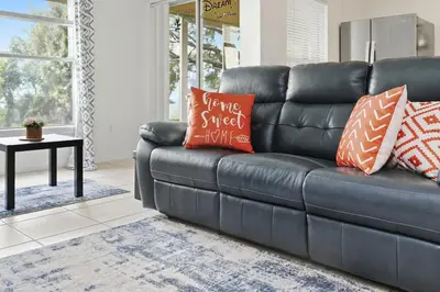 a black leather couch with orange pillows in a living room at Pond View Club Cortile Resort Pool Hot Tub Theme in Kissimmee