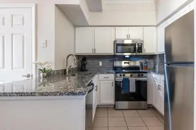 a kitchen with white cabinets and stainless steel appliances at Landing Beautiful 1BD Gym Pool in Orlando