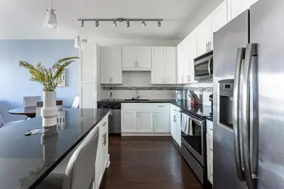 a kitchen with white cabinets and a stainless steel refrigerator at Landing Stylish 1BD Rooftop Lounge Gym in Orlando