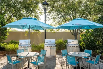 two tables and chairs with blue umbrellas at SpringHill Suites by Marriott Orlando at FLAMINGO CROSSINGS Town Center-Western Entrance in Orlando