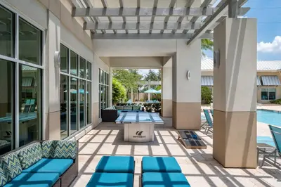a patio with blue chairs and a swimming pool at SpringHill Suites by Marriott Orlando at FLAMINGO CROSSINGS Town Center-Western Entrance in Orlando