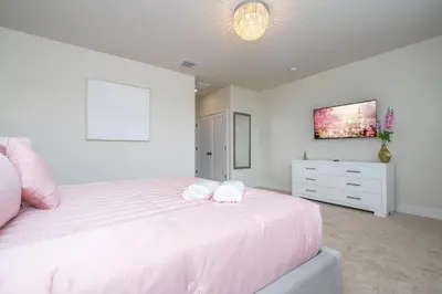 a bedroom with a large white bed and a dresser at Stylish Property with Private Pool in Orlando