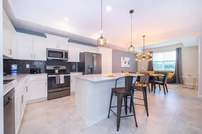 a kitchen with white cabinets and a table with chairs at Amazing Condo Getaway in Kissimmee