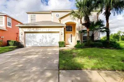 a house with a garage and palm trees at EIR2706 - 7B Lakefront Resort 8 min to Disney in Kissimmee
