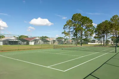 a tennis court with a net and some houses at Magical Family Getaway - 10ppl in Kissimmee