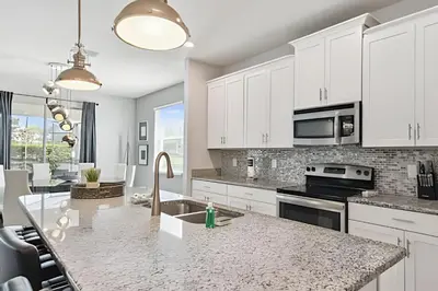 a kitchen with white cabinets and a granite counter top at Casa Luxo Storey Lake | 6 quartos + Piscina in Kissimmee