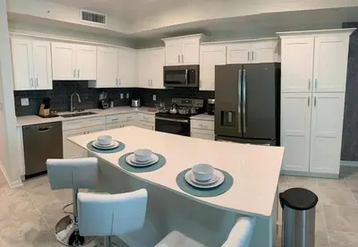 a kitchen with white cabinets and a island with dishes on it at To Infinity and Beyond – Storey Lake Resort by Shine Villas condo in Kissimmee