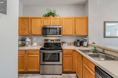 a kitchen with wooden cabinets and a stove top oven at Private Hot Tub near Disney Parks in Kissimmee