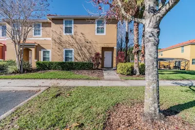 a house with a tree in the front yard at 15min to Disney · Modern Home Hot Tub in Kissimmee