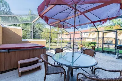 a patio with a table and chairs and an umbrella at 15min to Disney · Modern Home Hot Tub in Kissimmee