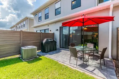 a patio with a table with a red umbrella at Themed Bedrooms BBQ Near Disney in Kissimmee