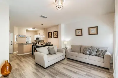 a living room with two couches and a kitchen at Family Home Near Disney – Modern Bright in Kissimmee