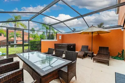 a patio with a glass table and chairs and an umbrella at 3BR Townhome Near Disney Free Jacuzzi in Kissimmee