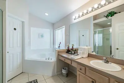 a bathroom with a sink and a tub and a mirror at Lake Berkley Getaway – 5BR Resort Home in Kissimmee