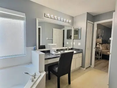 a bathroom with a sink and a tub and a chair at Lake Berkley Getaway – 5BR Private Pool in Kissimmee
