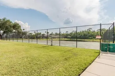 a chain link fence on a tennis court at Lake Berkley Getaway – 5BR Private Pool in Kissimmee