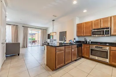 a large kitchen with wooden cabinets and appliances at 2BR Villa Near Disney Resort Amenities in Kissimmee