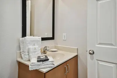 a bathroom with a sink with a mirror and towels at Encantada Resort 15min Disney in Kissimmee