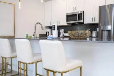 a kitchen with white cabinets and white bar stools at Family Retreat near Disney in Kissimmee