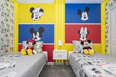 two beds in a room with mickey mouse wallpaper at Family Retreat near Disney in Kissimmee