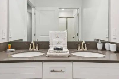 a bathroom with two sinks with towels and a mirror at 4BR Townhome Near Disney Water Park in Kissimmee