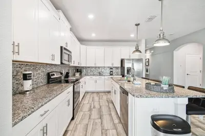 a kitchen with white cabinets and marble counter tops at Luxury Family Retreat Near Disney in Kissimmee