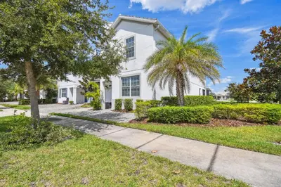 a white house with a palm tree and a sidewalk at Luxury Family Retreat Near Disney in Kissimmee